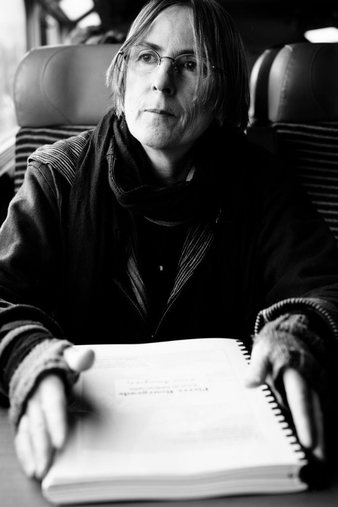 Marie Morel dans le TGV Paris-Bourg en Bresse. Elle est en train de lire un ouvrage bibliographique sur son ami Pierre Bourgeade récemment décédé. Elle revient d'une réunion parisienne où s'est crée une association pour perpétuer le travail de l'écrivain Pierre Bourgeade.