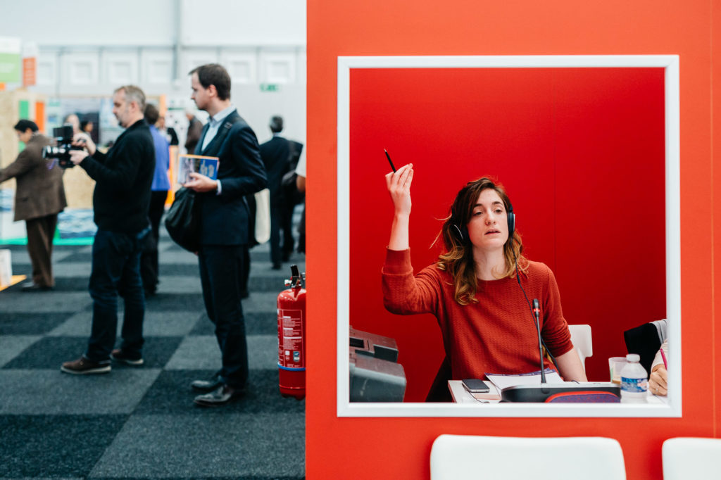 Le Bourget. 3 décembre. À l'espace Génération Climat, Jessica Le Briquer traduit de l'anglais vers le français, la parole d'un activiste indonésien lors d'une conférence. Elle est l'une des centaines d’interprètes présents sur le site de la COP21 pour assurer la traduction en direct des débats (dans plus de 6 langues) et des négociations (en français et anglais). Même si l'anglais est largement parlé sur le site, les interprètes ont le rôle de ne laisser aucun participant de côté.