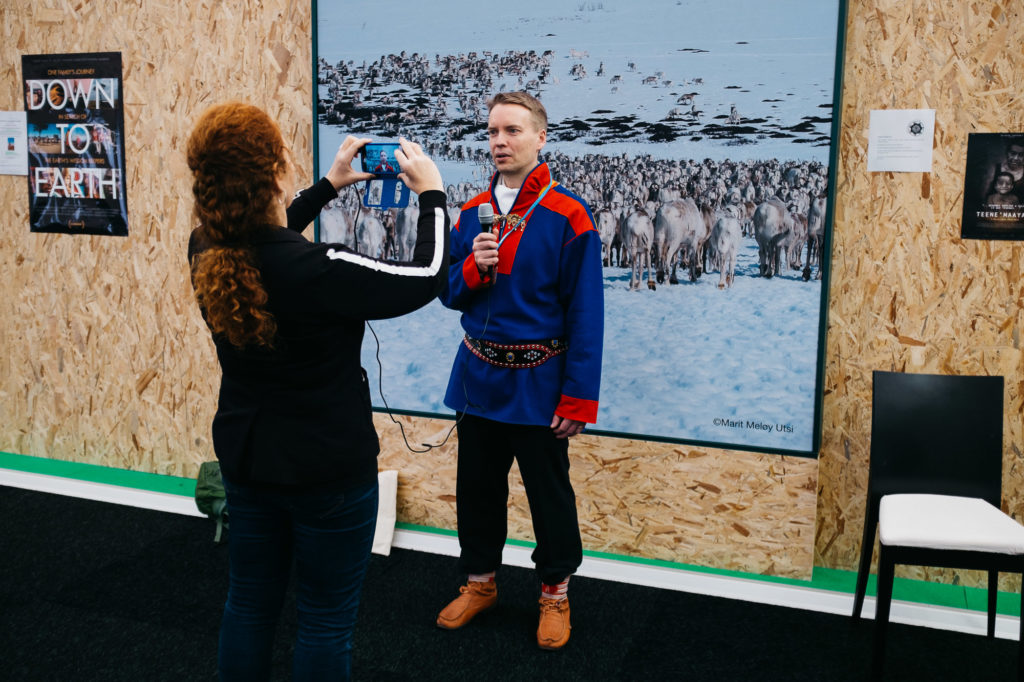Le Bourget 8 décembre. Un journaliste réalise une interview devant une photo prise au-delà du cercle polaire à l'espace Génération Climat ouvert au public. De nombreux pays et organisations du monde entier présentent leurs problèmes et solutions face aux changements climatiques. Les visiteurs ont le loisir de faire un tour du monde dans l'espace très standardisé et moderne du salon du Bourget.