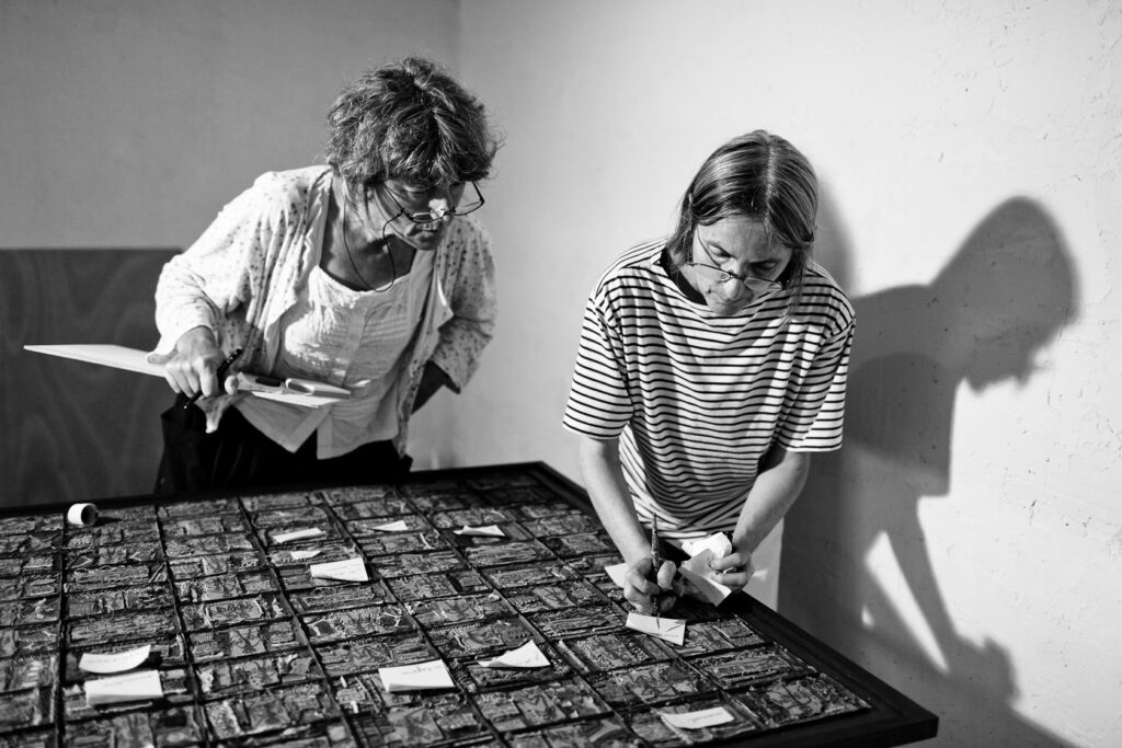 Marie Morel et Claudine Vallot corrigent les fautes d'orthographes d'un tableau de 1990 avant sa reproduction photographique.