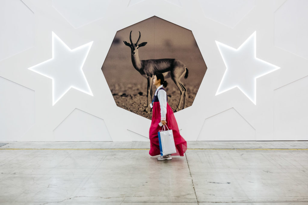 Le Bourget. 10 décembre. Une déléguée de Corée du Sud passe devant le pavillon imposant et tappe à l'oeil  des états du Golfe (Qatar, Bahreïn, EAU, etc.)