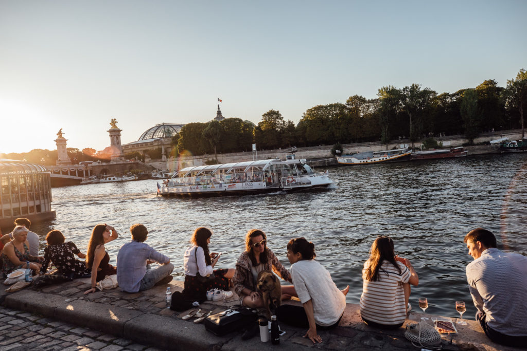 See the major sights of Paris from the water on a hop-on hop-off Seine boat cruise. 
People are having a picnic on the Seine riverbanks at sunset, Paris, on July 29th, 2019.