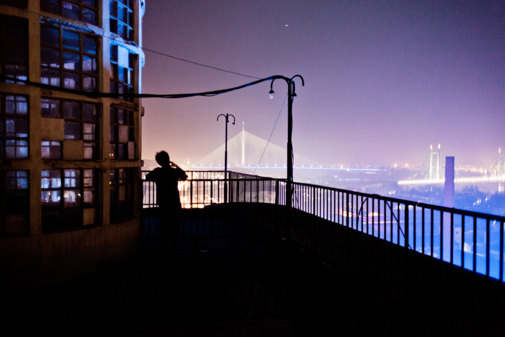 Un serveur prends sa pause et fume une cigarette depuis la terrasse du Jazz Club Čekaonica ouvert en mai 2011 au dernière étage de l'immeuble BIGZ (qui abritait L'ancienne imprimerie nationale de Yougoslavie). Ce lieu abrite aujourd'hui des artistes, une salle de cirque, des studios de musique, des start-up et de ce jazz club qui bénéficie d'une terrasse panoramique sur toute la ville. La capitale serbe est en passe de devenir l'une des villes européennes les plus attractive en ce qui concerne la vie nocturne et la culture alternative. /// A barman takes his break and smokes a cigarette in the Jazz Club Čekaonica terrace open since 2011 May at the top floor of BIGZ Building (where was the old Yougoslavia government publications office). This place host currently artists, circus room, music studios, start-up & this jazz club with a large balcony which have a panoramic view to all the city. The Serbian capital is becoming one of the most attractive european city about night life and underground culture.